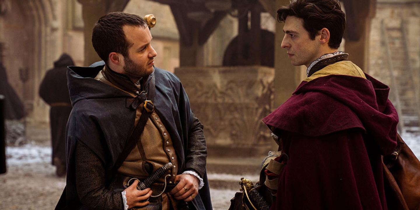 Two men in Tudor clothing converse in a street