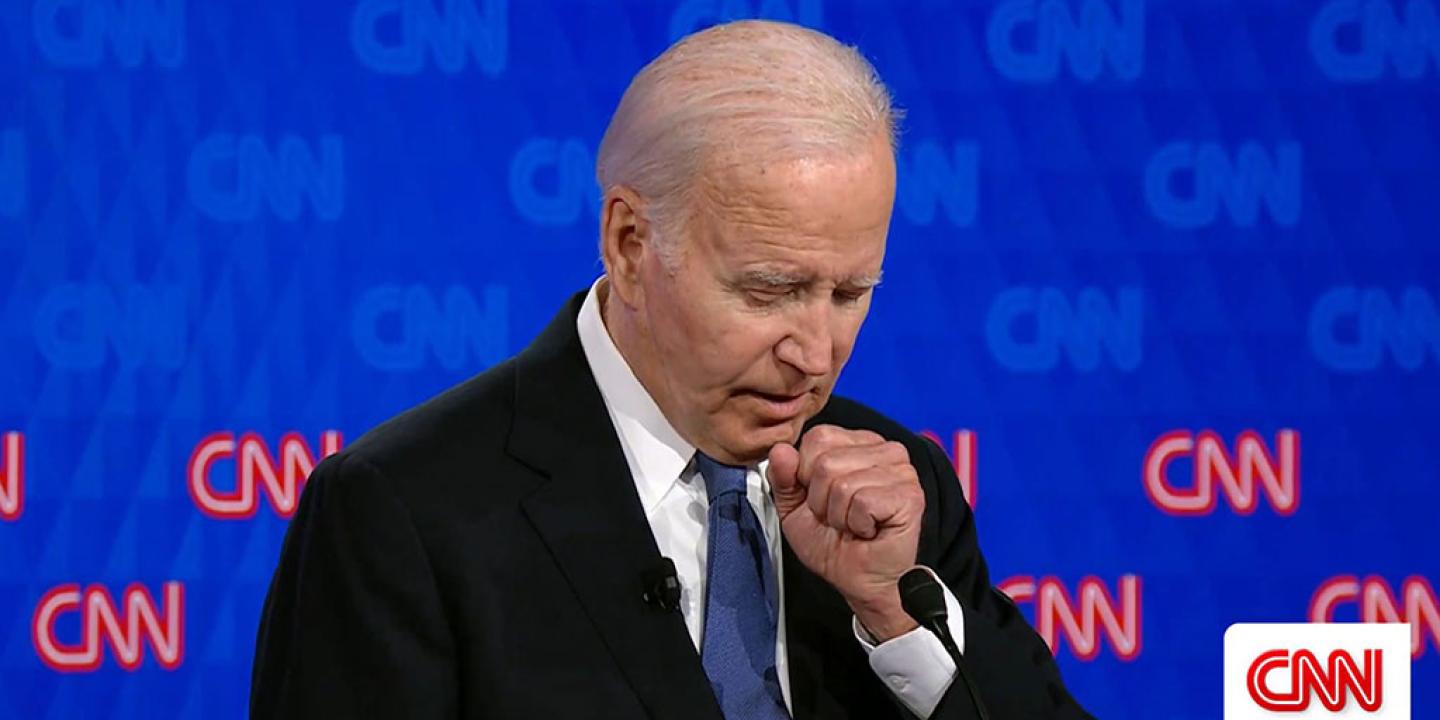 Joe Biden holds a fist to his chest as he stands and speaks.