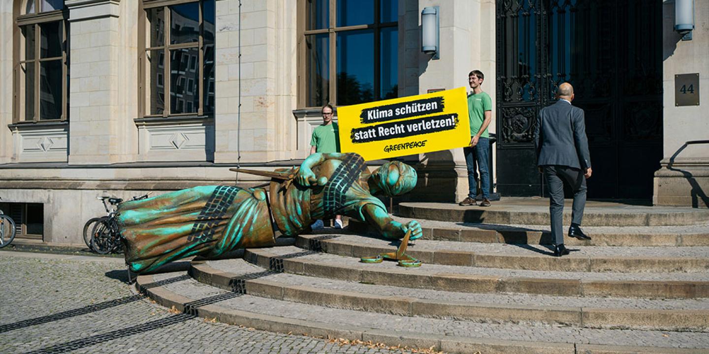 A fallen statute with tyre tracks over it lies on the steps to a government building, in a form of protest.