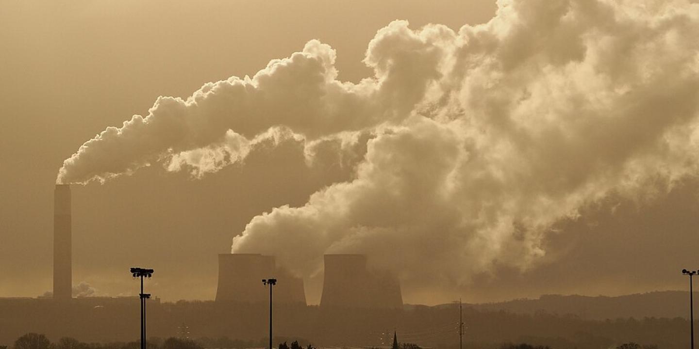 A sky line shows steam rising from a power station's chimney and cooling towers.
