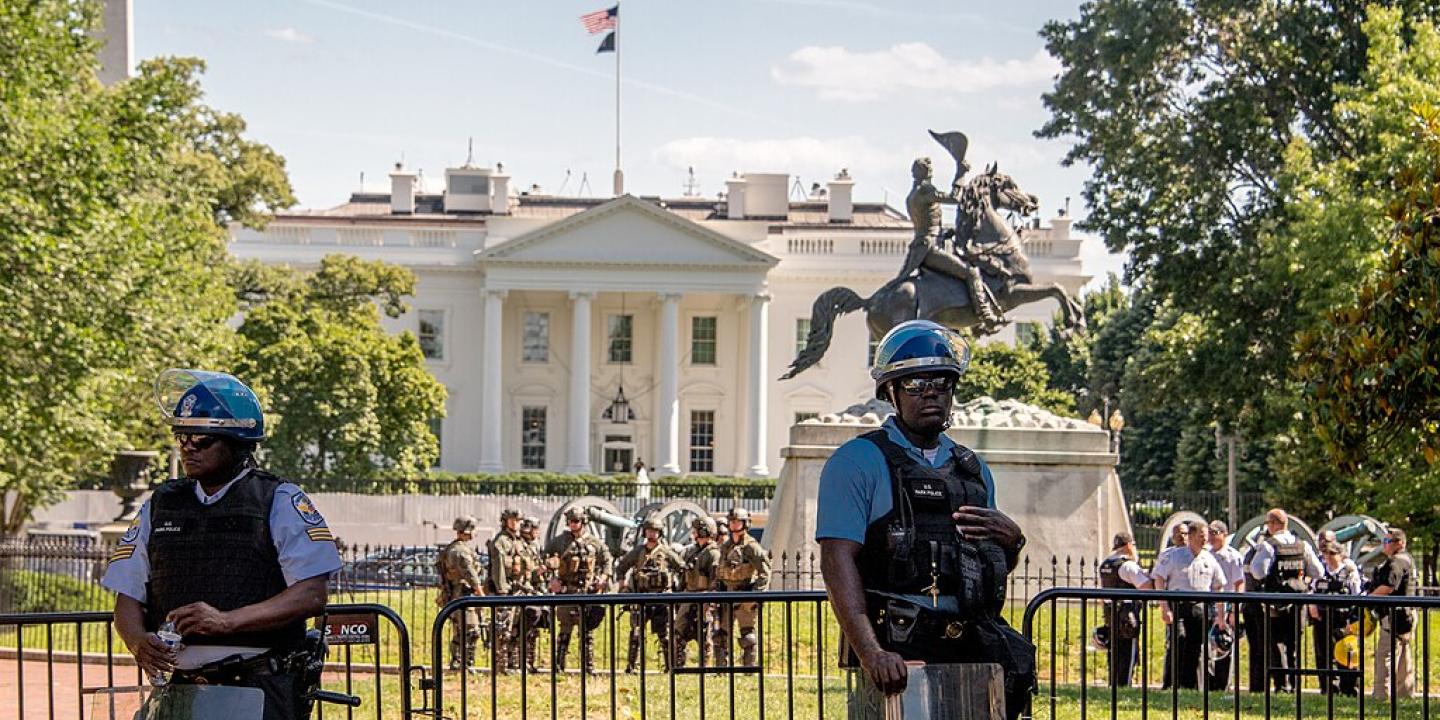 Riot police stand guard outside a White House fence line. 