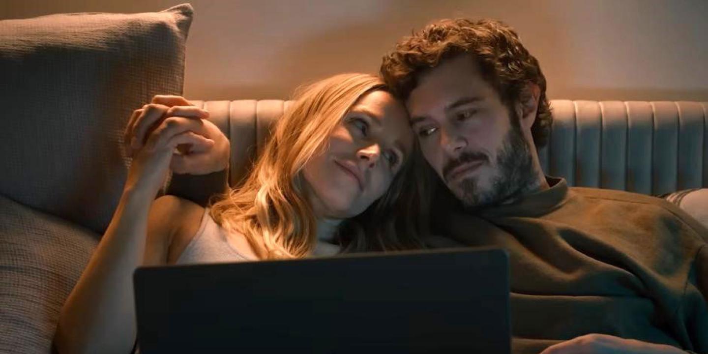 A couple together on a sofa watch a laptop,