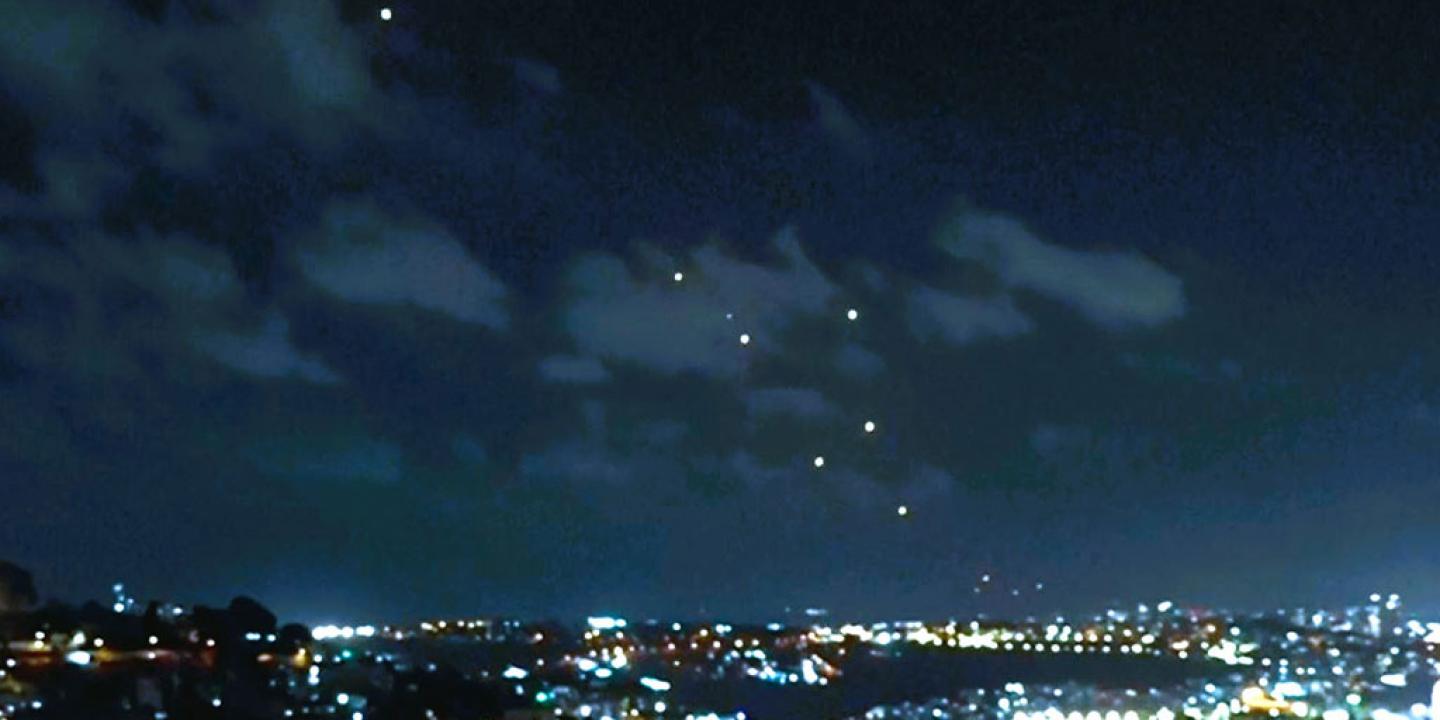 Dots of light, caused by missles, fall across a night sky above the city