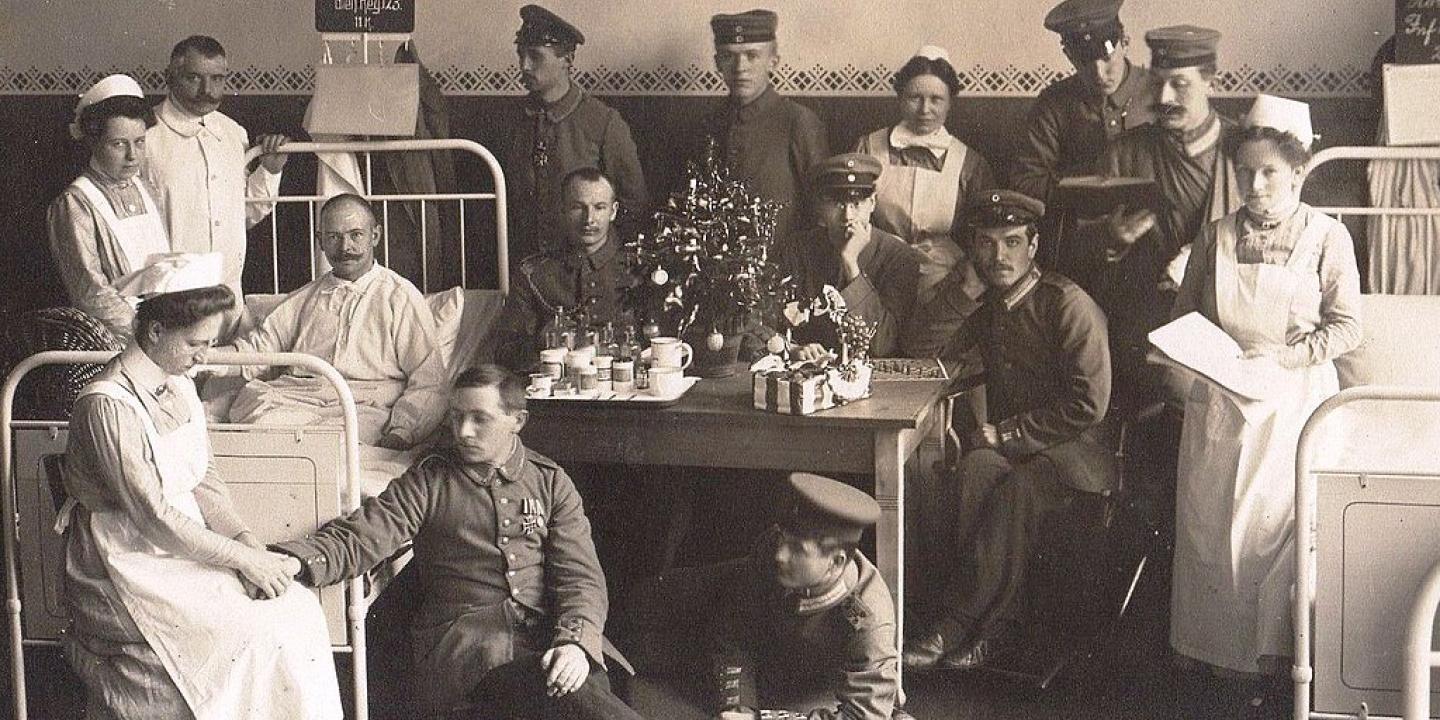 A black and white photo shows solider patients and nurses in a hospital.