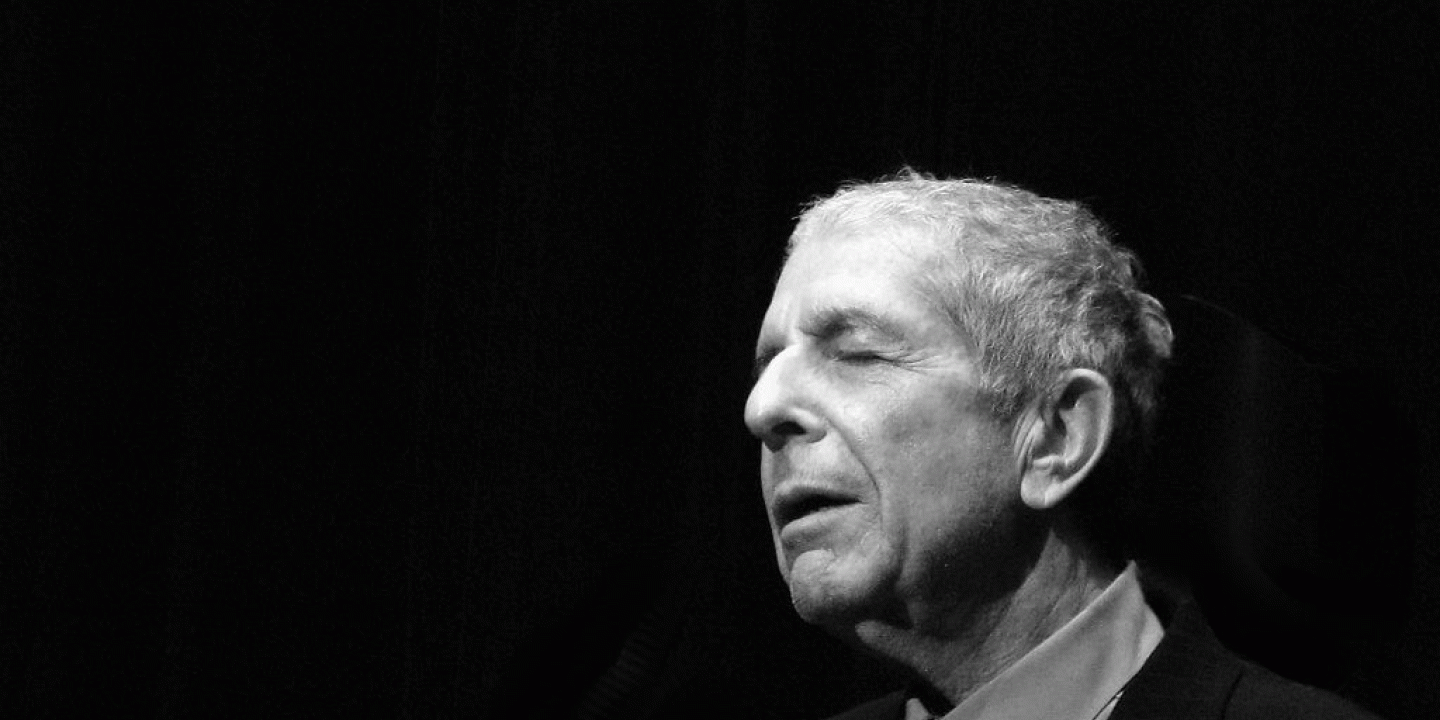 A black and white photo shows, singer Leonard Cohen to the right hand side, eyes closed and head inclined slightly upwards.