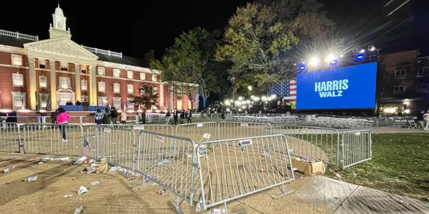 Crowd barrier surround empty space at a night time political rally.