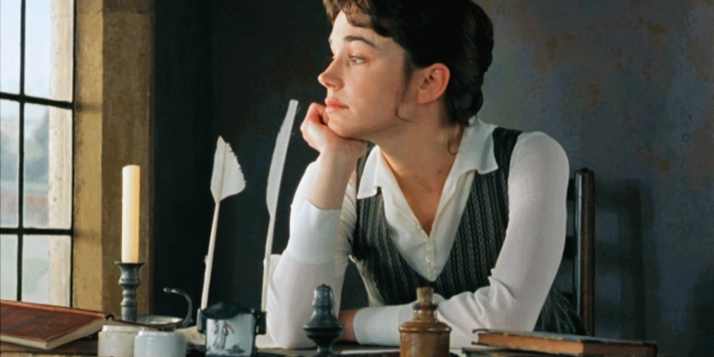 A 18th century woman sits at a desk, beside a candle and stares out the window.
