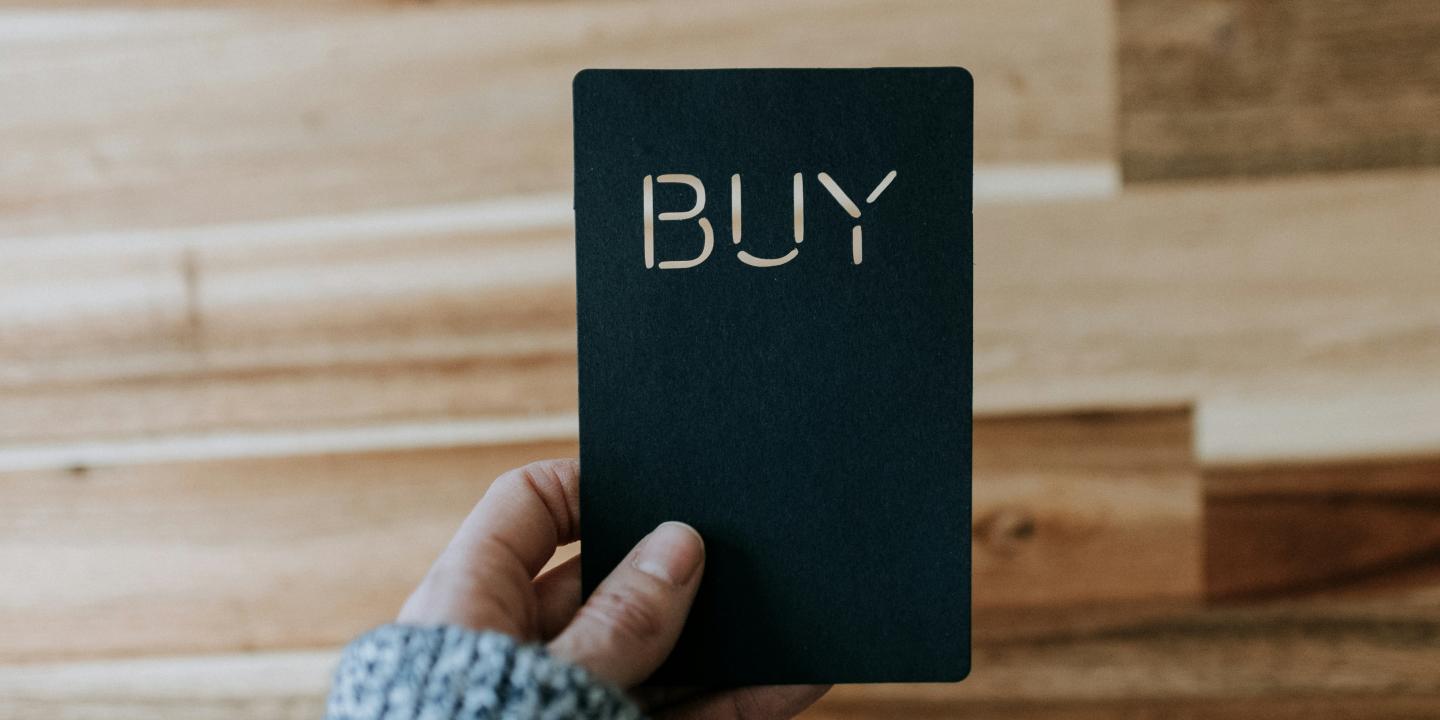 a hand hold a black payment card that reads 'buy'.