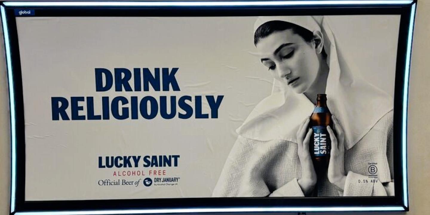 A subway billboard ad show a nun cradling a beer.