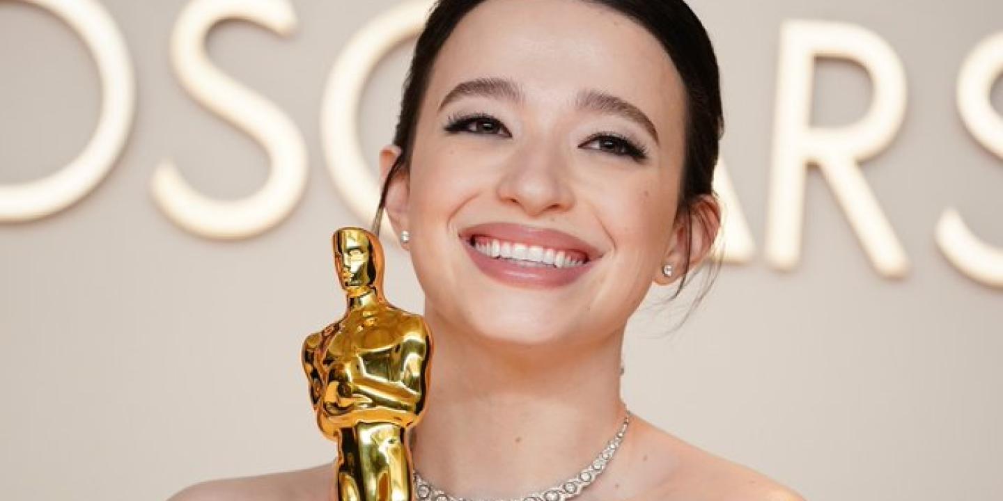 Mikey Madison, wearing a ball gown, clutches a golden Oscar statue.
