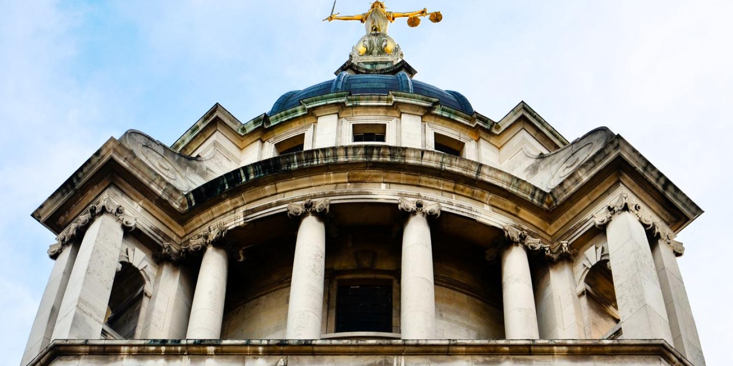 A classical court house with a statue on top of a dome.