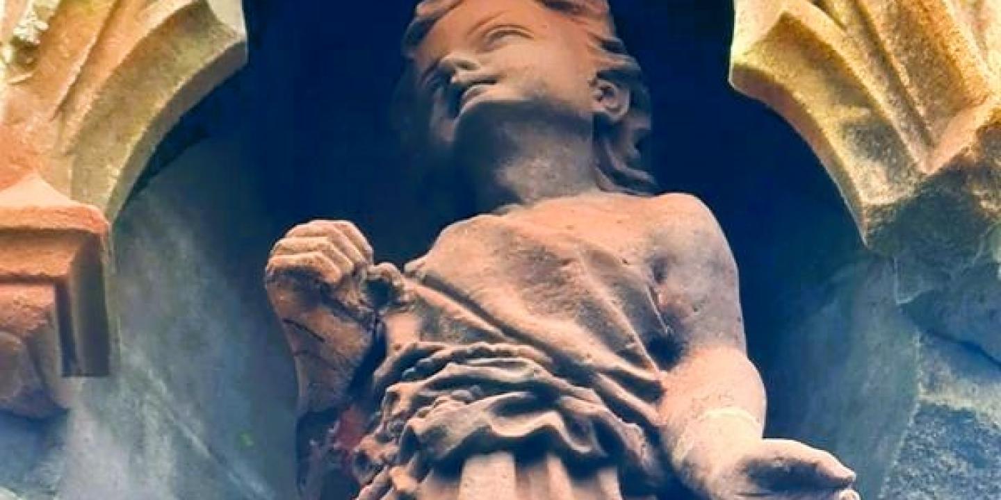 A red sandstone statue of Jesus as a child.