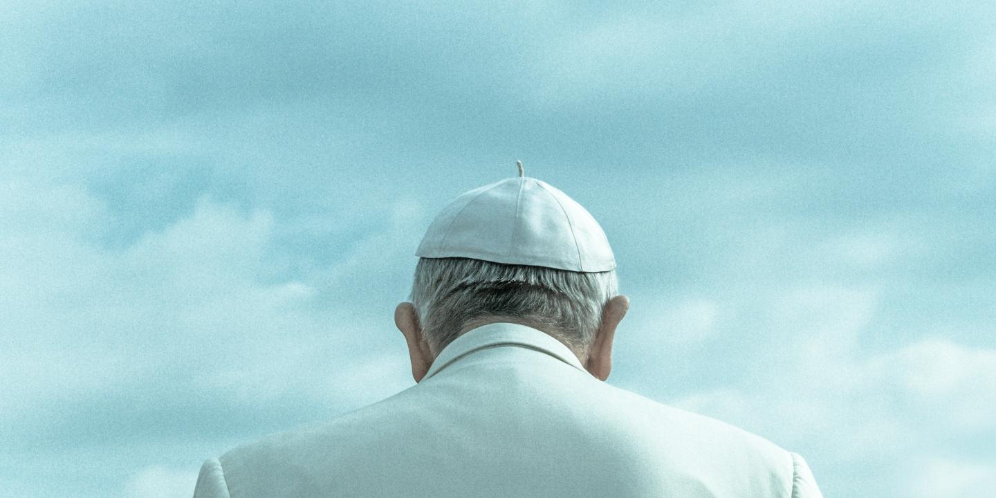 A pope wearing a white skull cap and white robe, viewed from behind