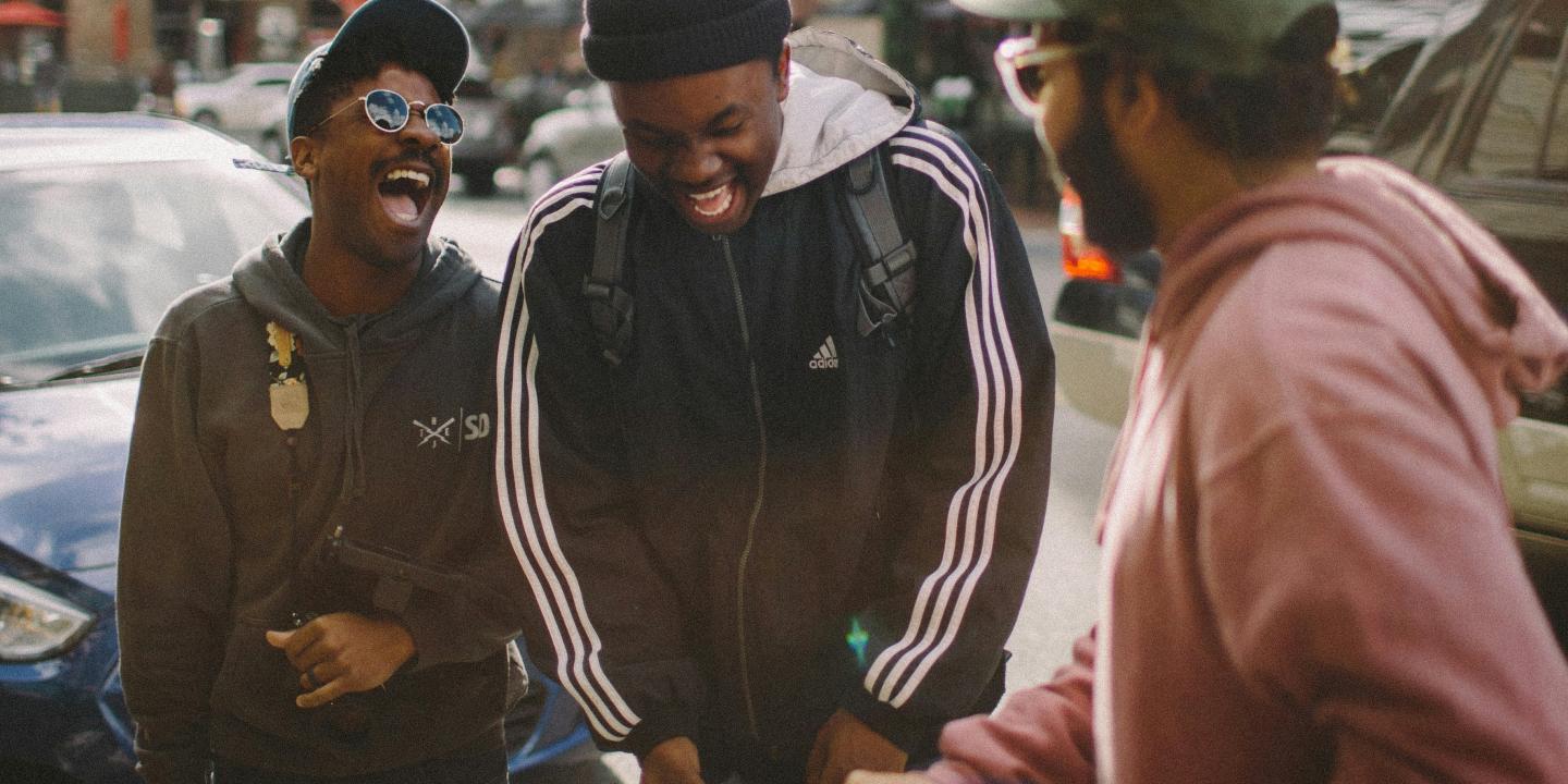 Three friends in the street laugh together.