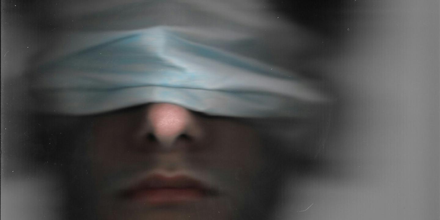 A blurred image of a blindfolded man.