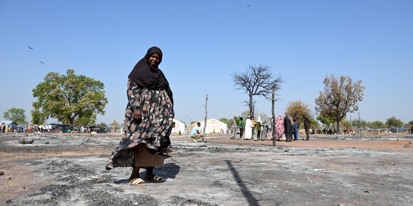 A Sudanese woman walks across the ashes of a burnt out street market.
