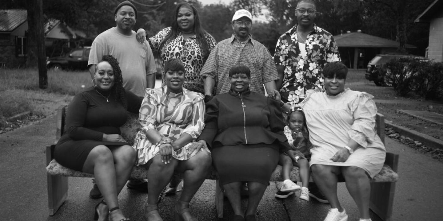 A family group stand and sit for a photo.
