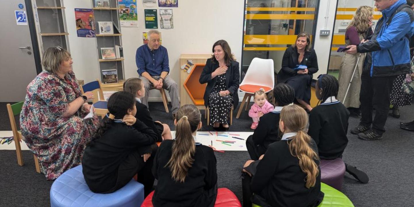 Children sit in a library listening to a story