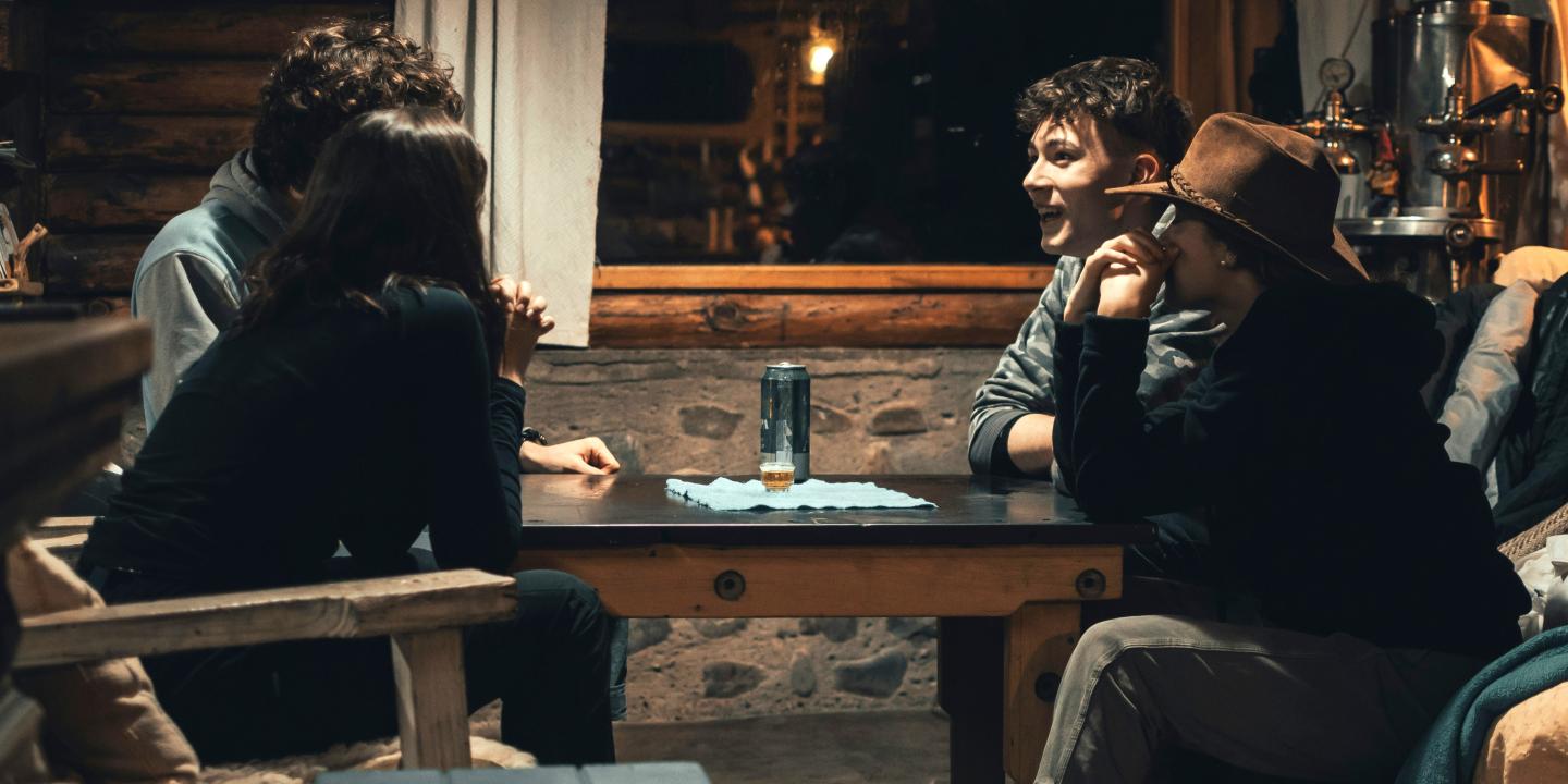 Four people sit round a pub table, some look animated, others pensive.