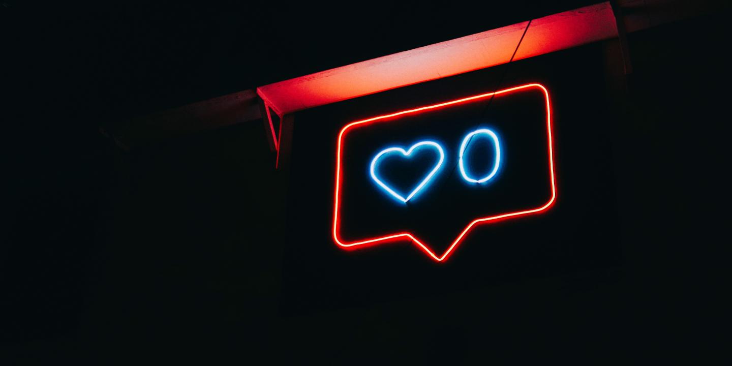 A neon sign depicts a message balloon with a heart symbol and a zero next to it.