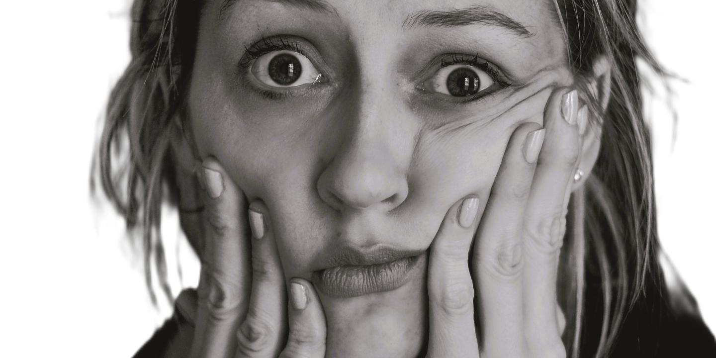 A perplexed looking woman hold her cheeks up with her fingers.