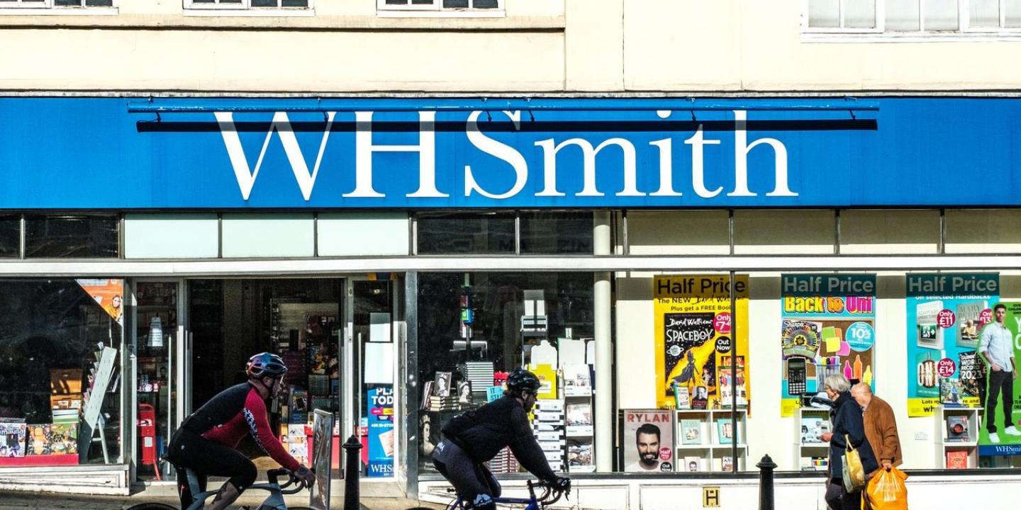 Cyclists and pedestrians pass in front of a WH Smith store front.