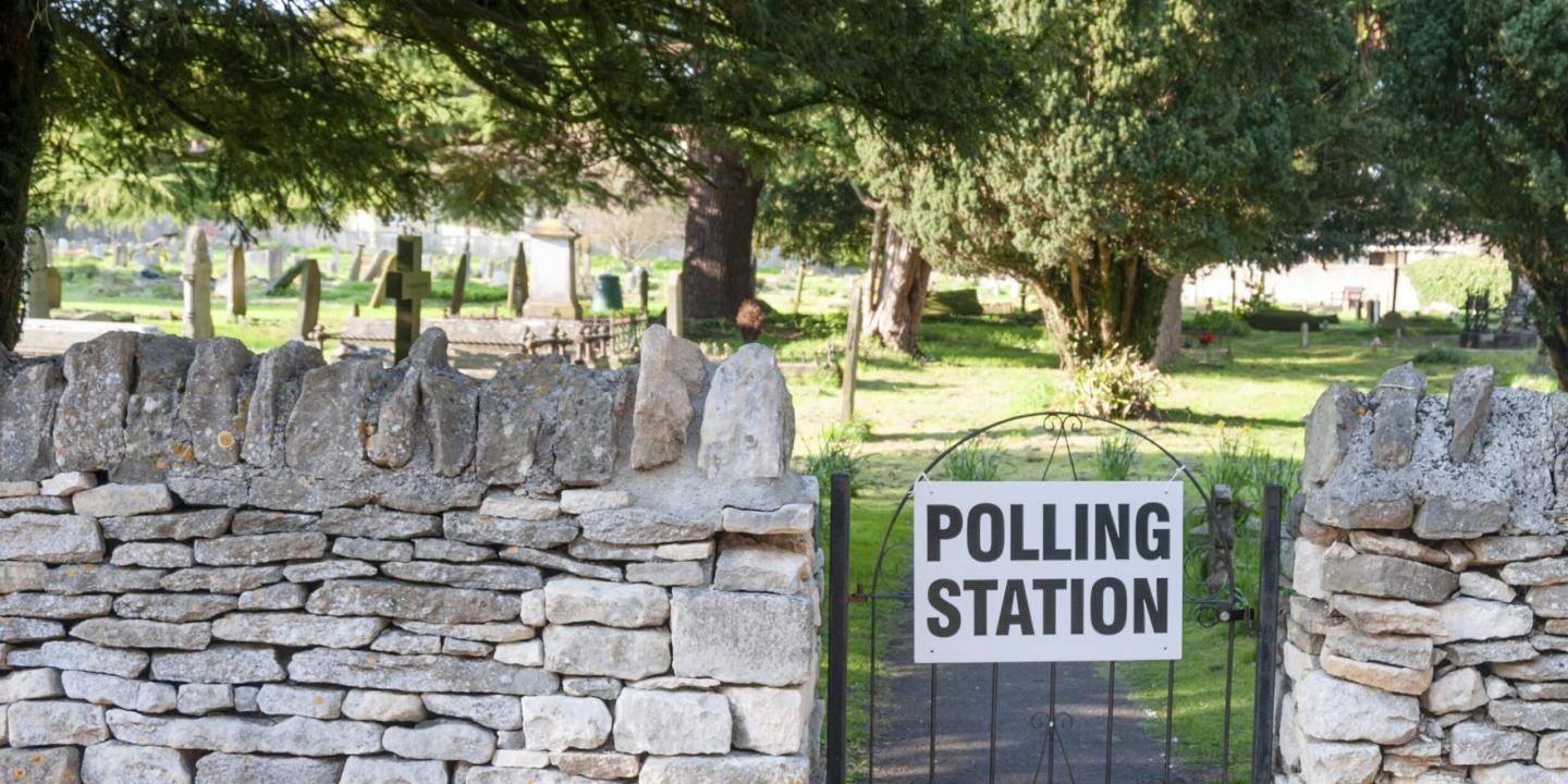 A gate to a churchyard displays a sign saying polling station.