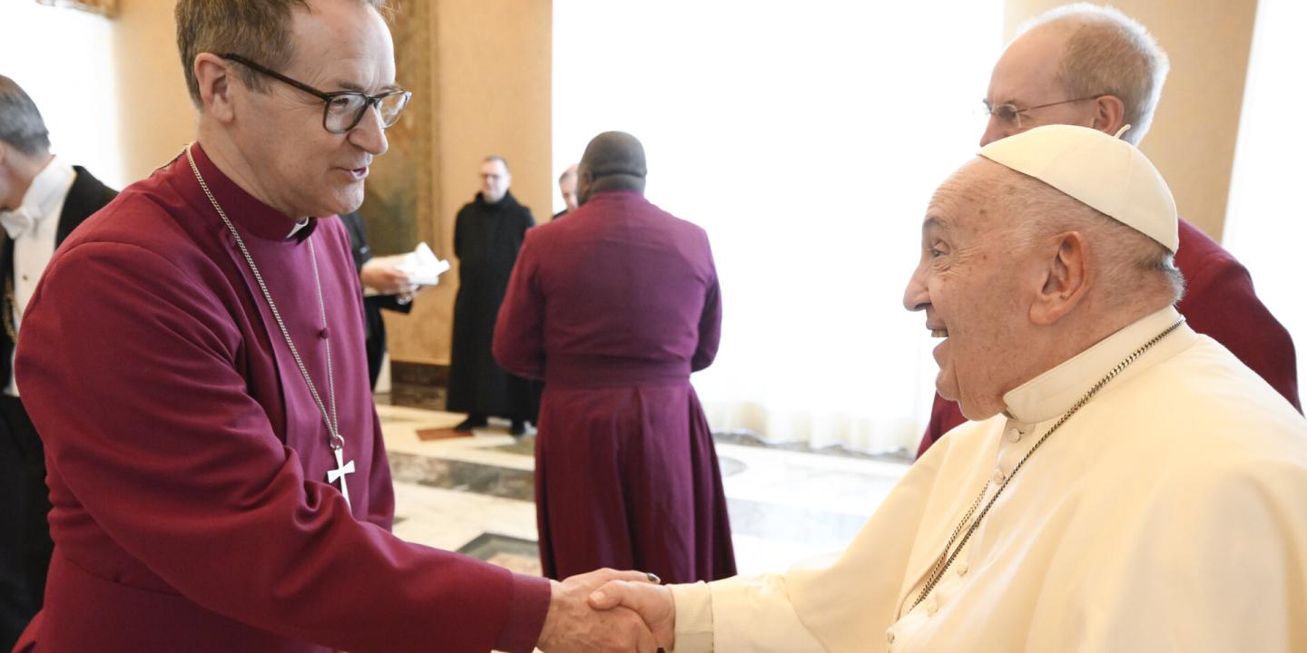 An Anglican bishop wearing purple shakes hands with the Pope.