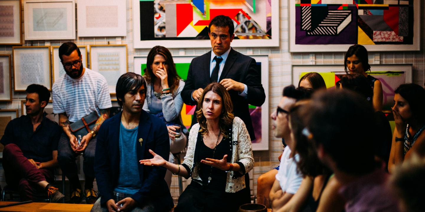 A member of an audience makes a point while gesturing.