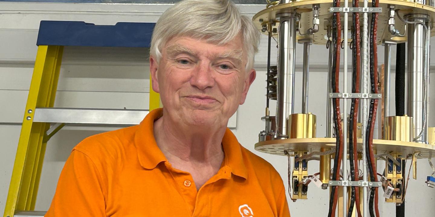 A professor stands next to experimental equipment.