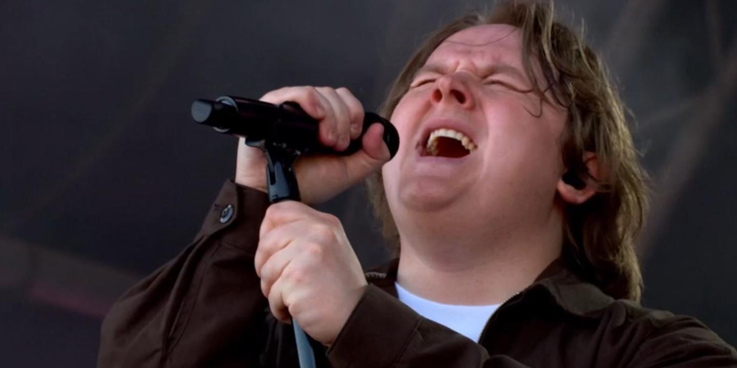 Lewis Capaldi sings with eyes closes, holding a mic and its stand