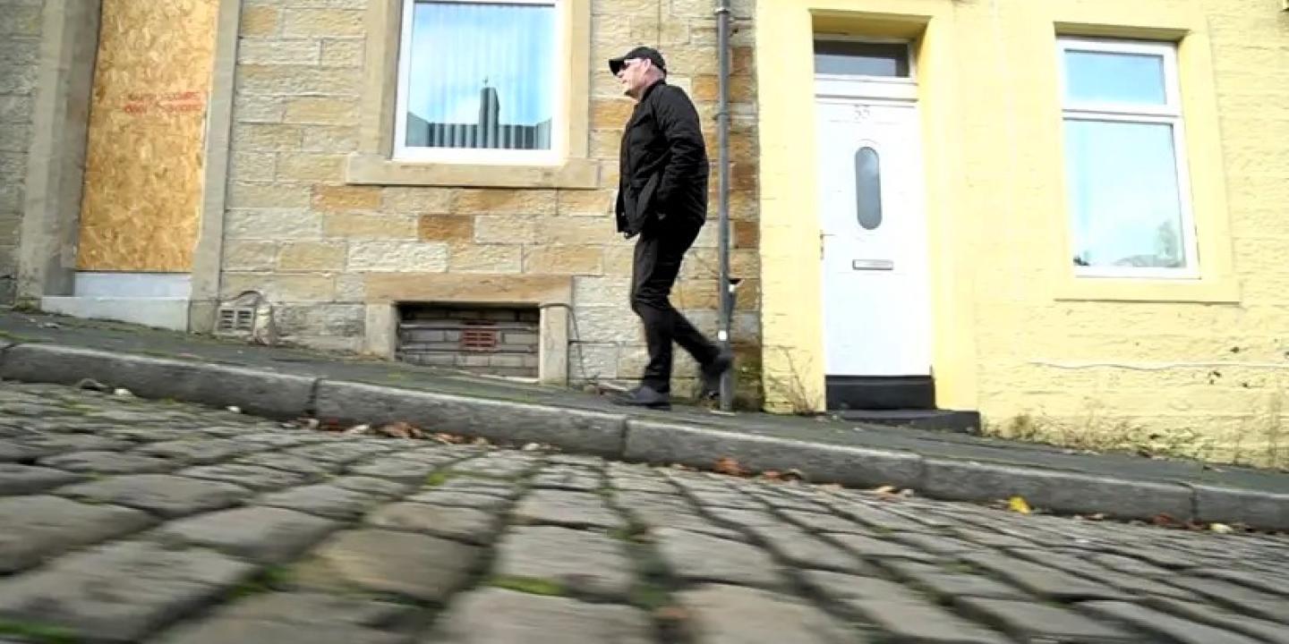 A man walks up a cobble street.
