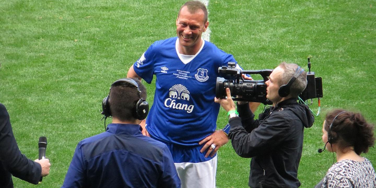 A footballer is interviewed on the side line.