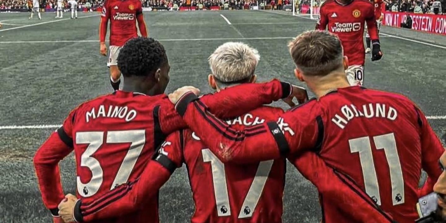 Three Manchester United footballers with their arms around each others backs.