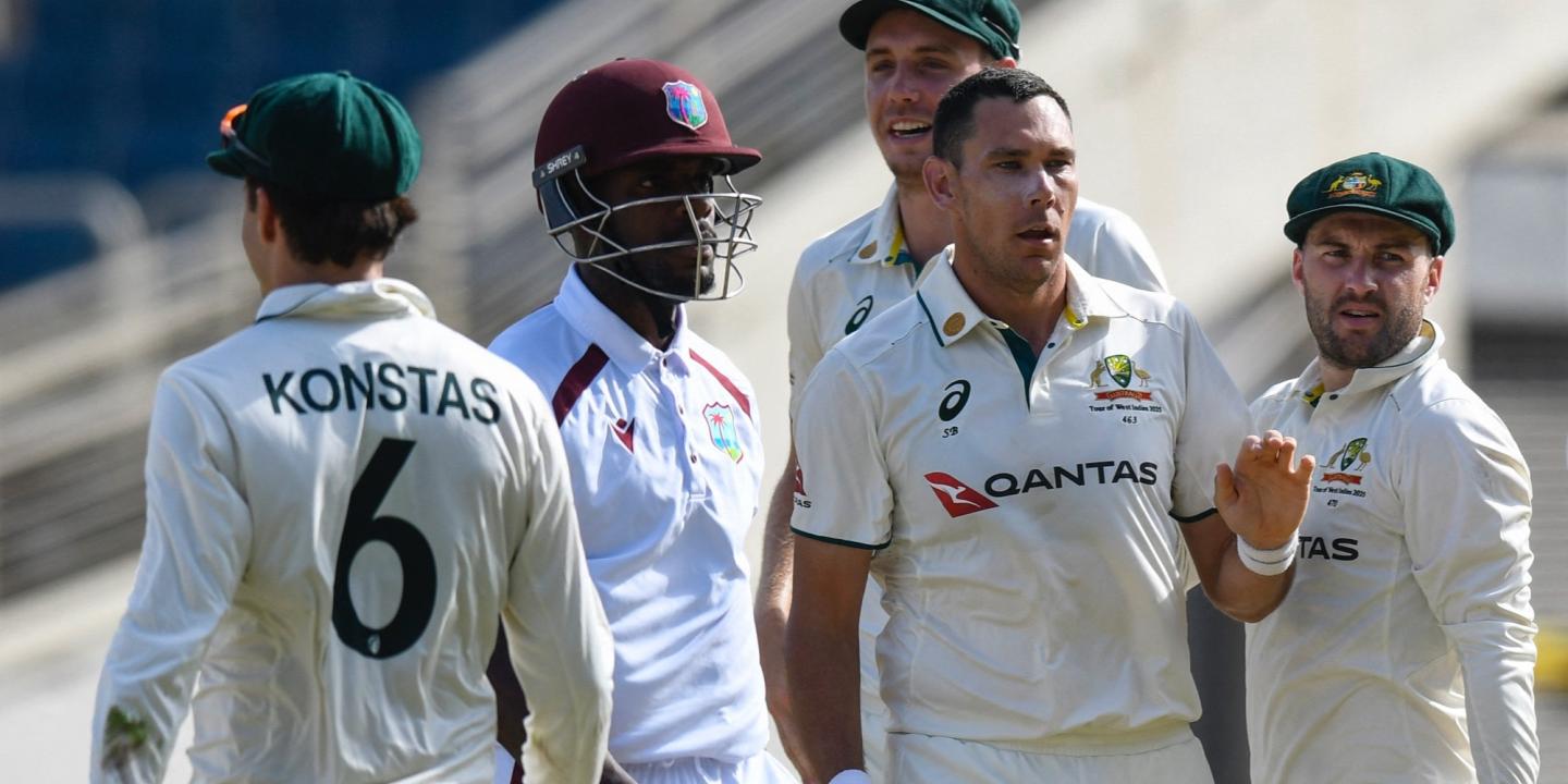 A cricket batsman surrounded by opposition players leaves the crease.