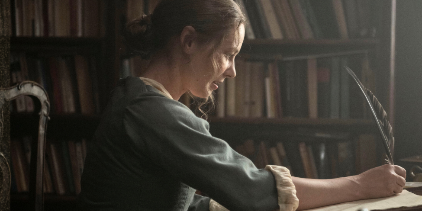A regency woman writes with a quill