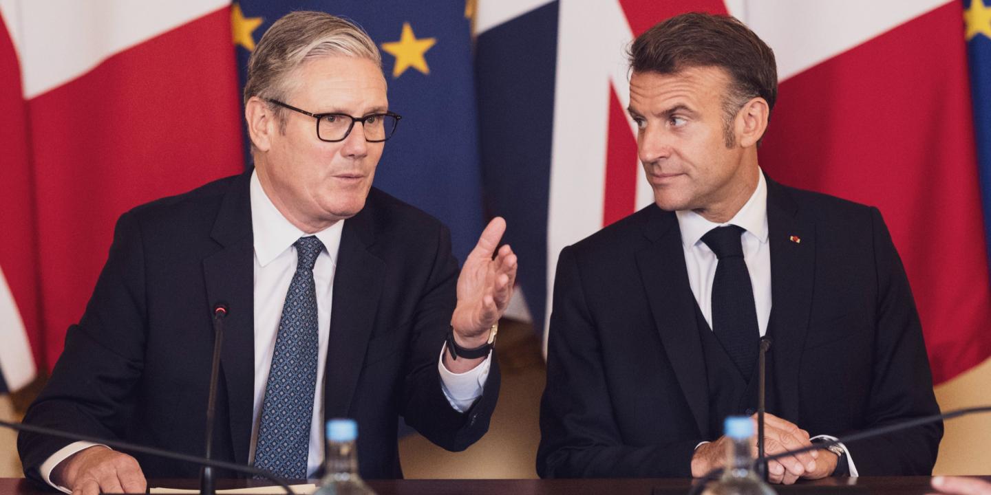 Keir Starmer and Emmanuel Macron in front of flags.