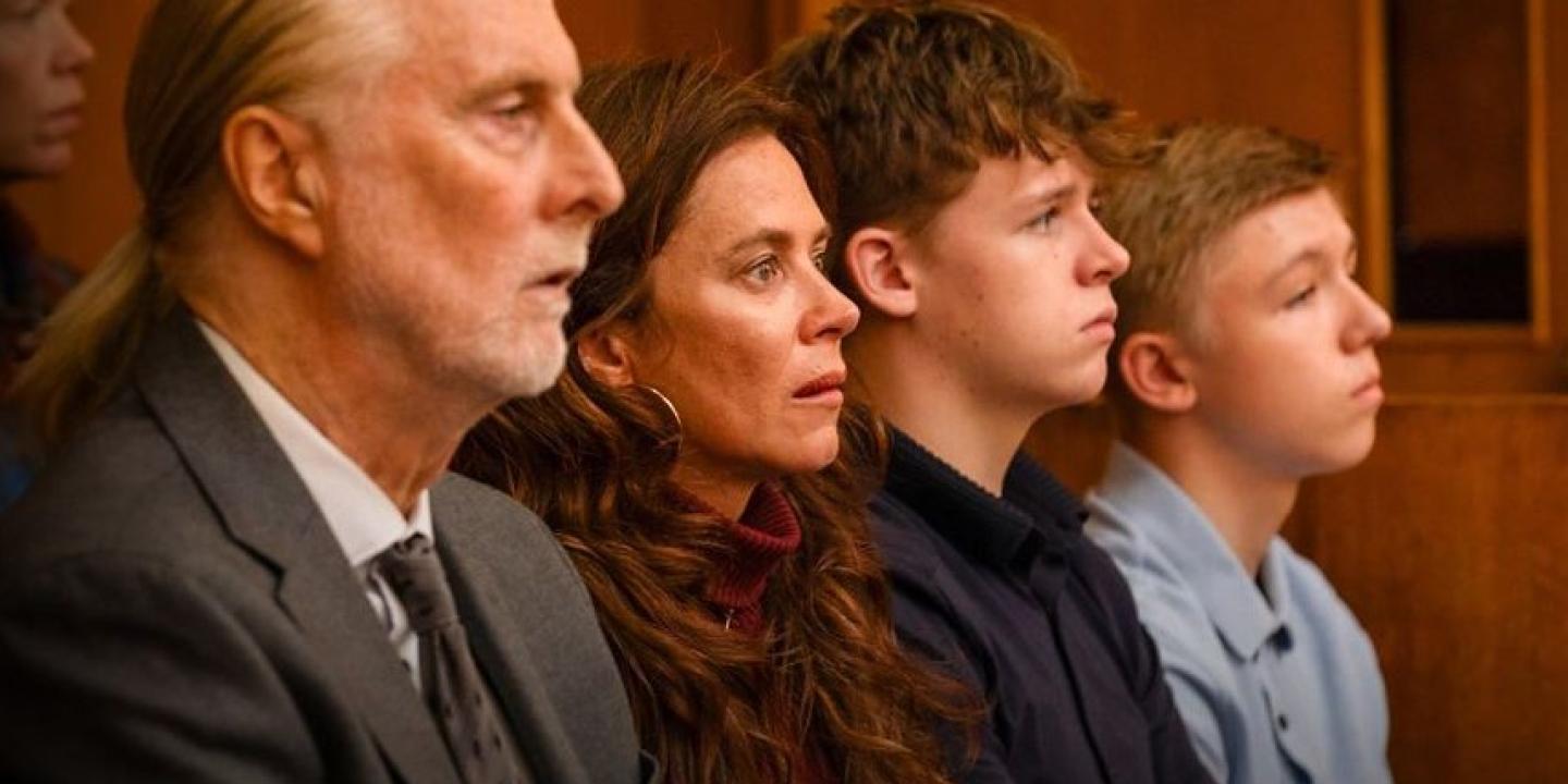A family sit together watching a trial in a court.