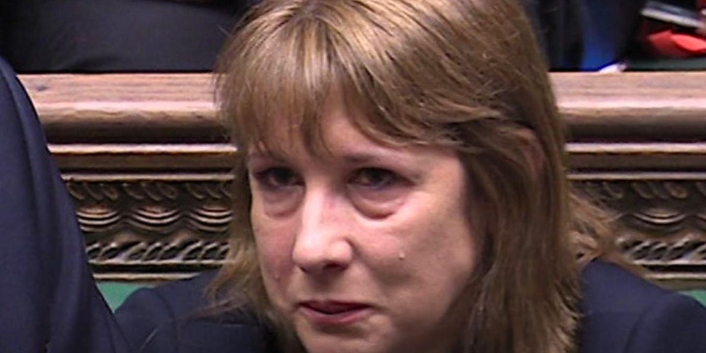 A woman sits and holds back a tear.