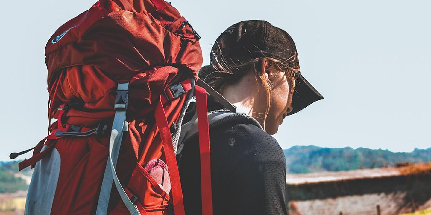 A pilgrim with a red backpack heads off.