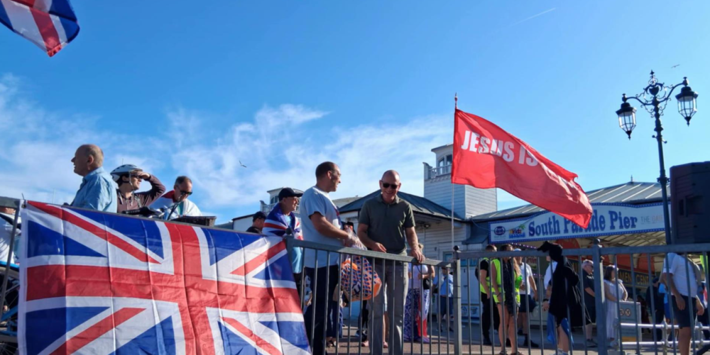 A Union Jack is draped over a railing, next to a red flag saying Jesus.