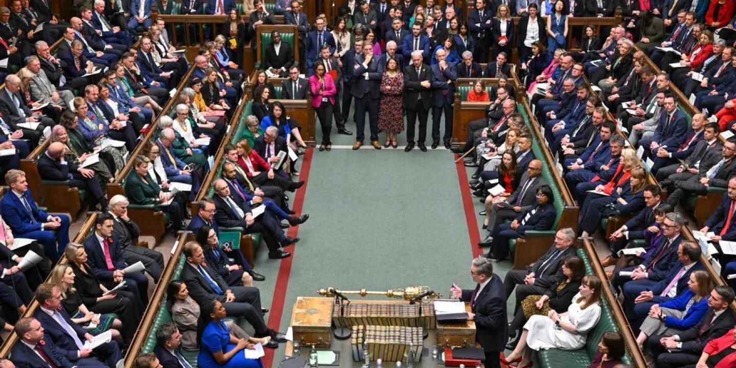 MPs sit and stand in a crowded parliament.