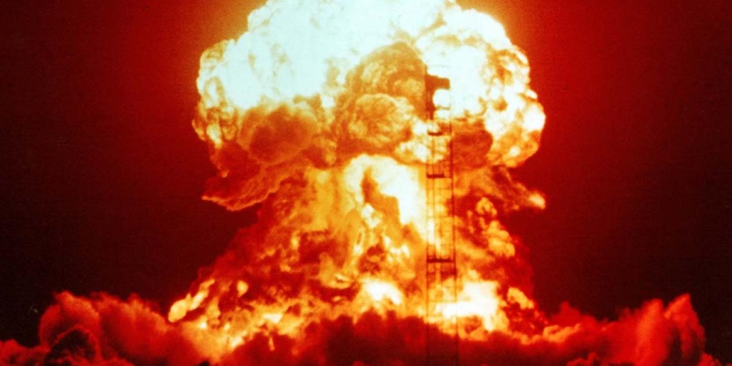 A nuclear explosion glows red and orange against the night sky.