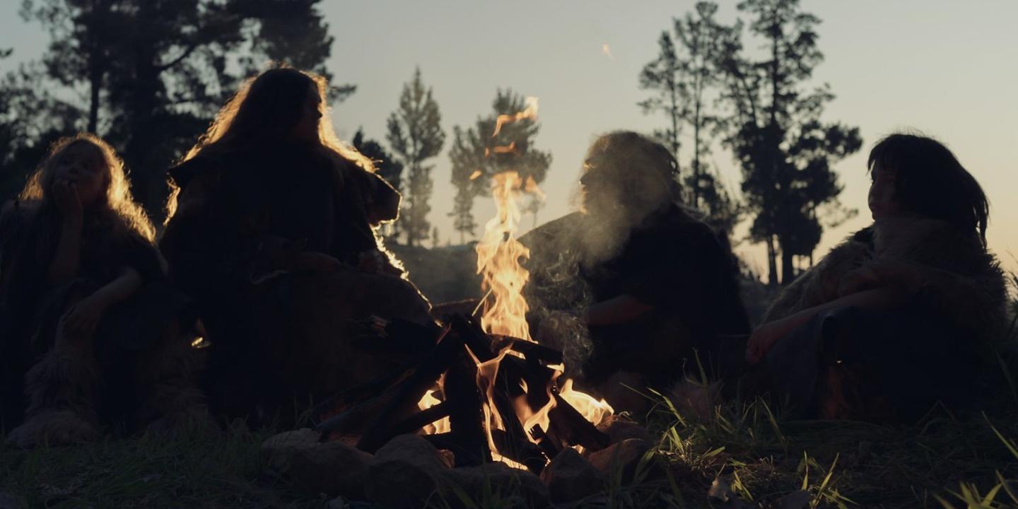 A re-enactment of an ancient 'caveman' family sitting around a camp fire.