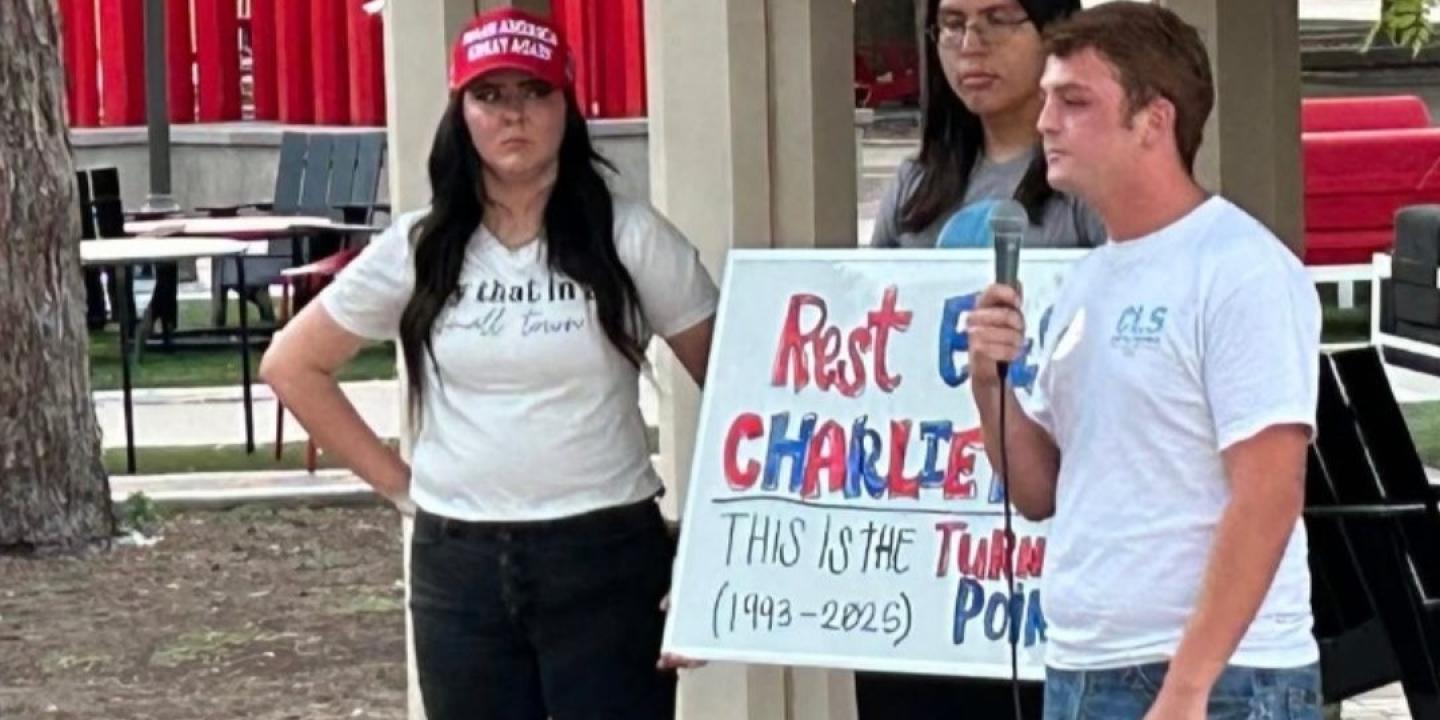Mourning students at a vigil hold a sign about Charlie Kirk.