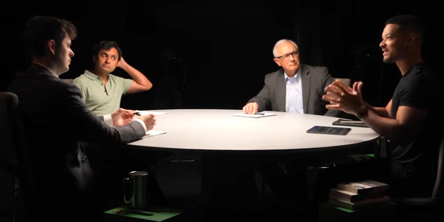A spotlit round table with podcast guests around it.