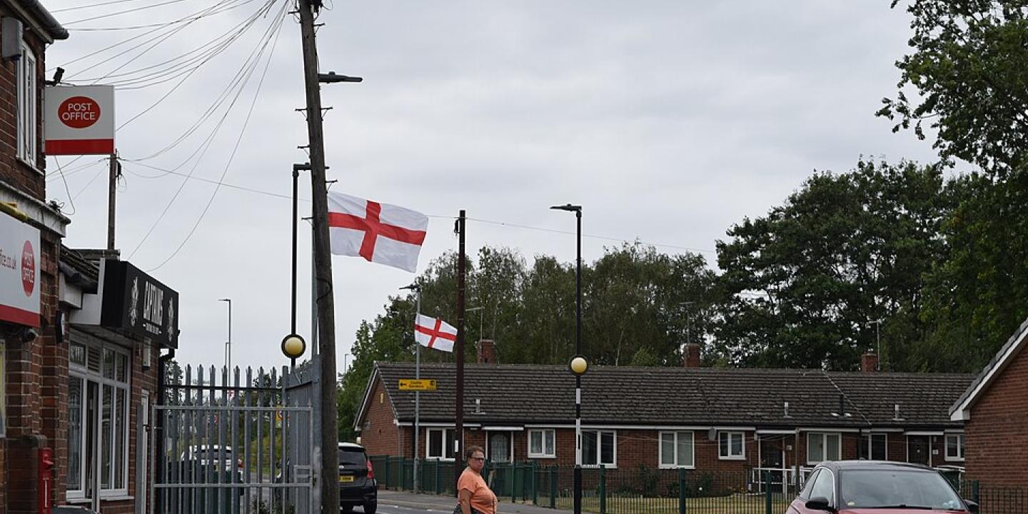 A suburban English street with St George's Cross flags on lamposts. 