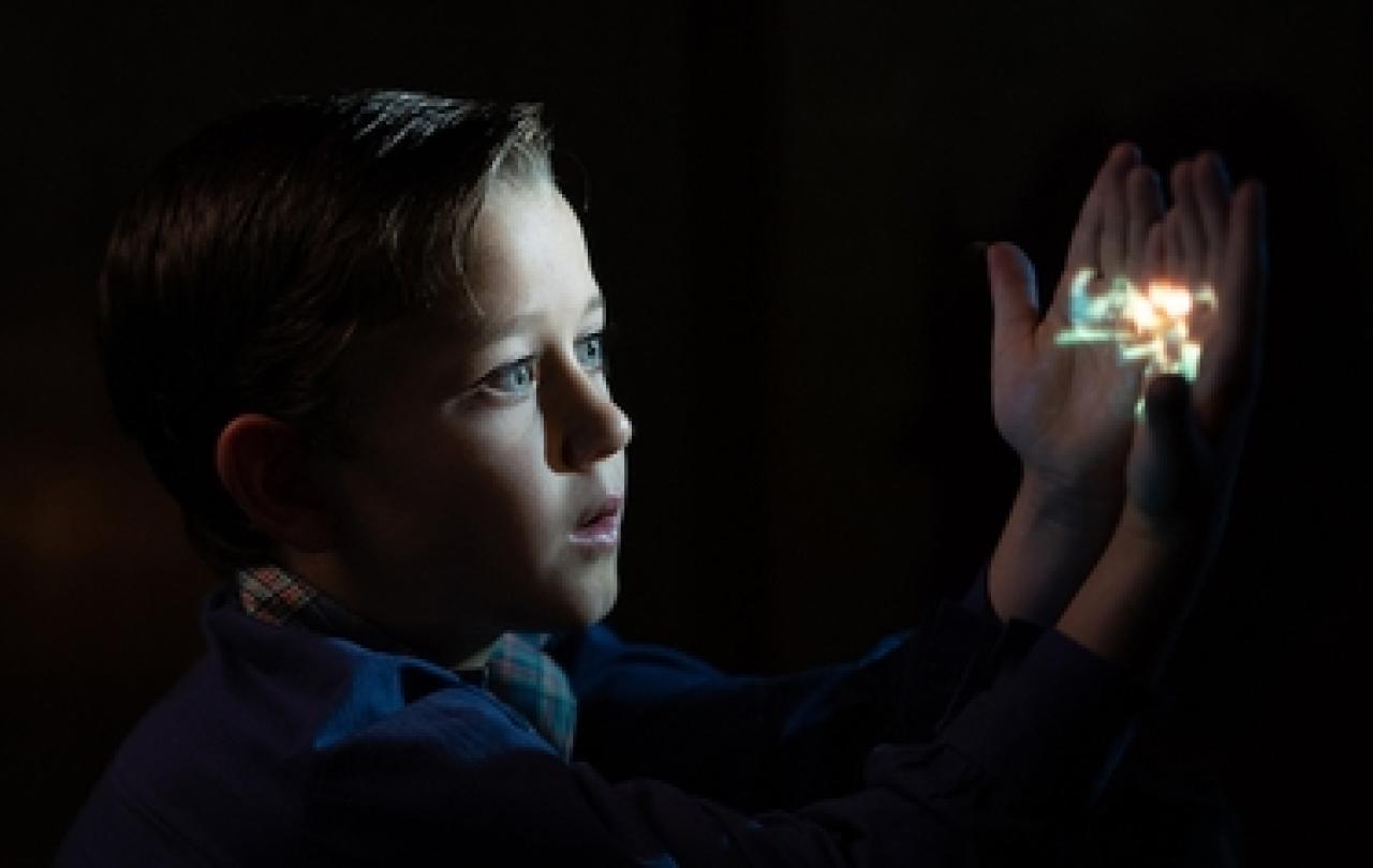 A cinematic view of a child holding an image that lights up their face.