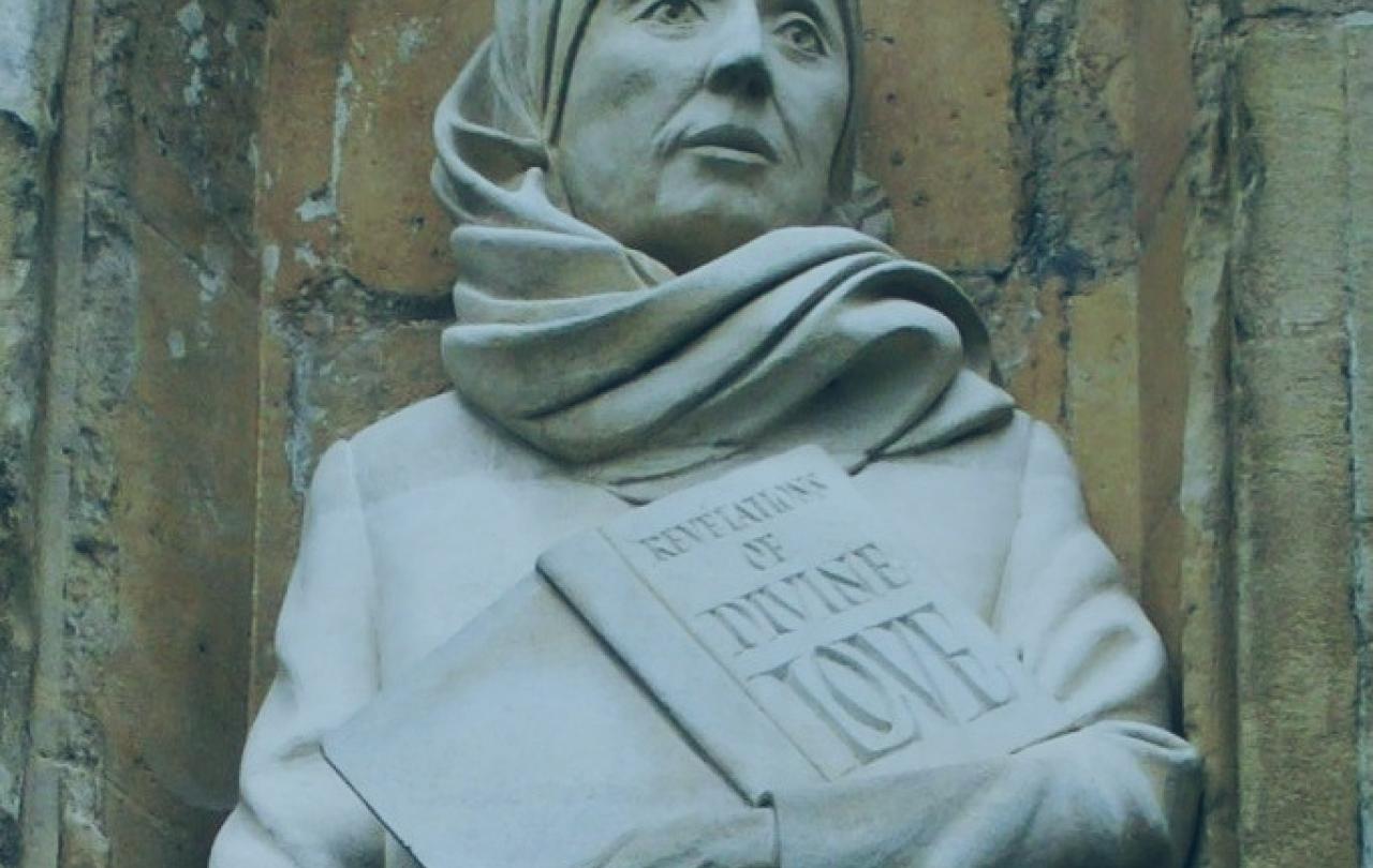 A statue of a Medieval women wearing a headscarf, and holding a book inscribed: revelation of divine love.o