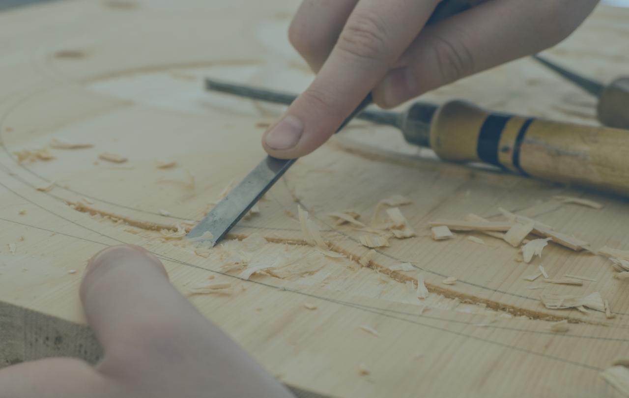 A carving tool is pressed into a groove in wood.